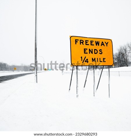 Snow covered highway with sign reading Freeway ends quarter mile.