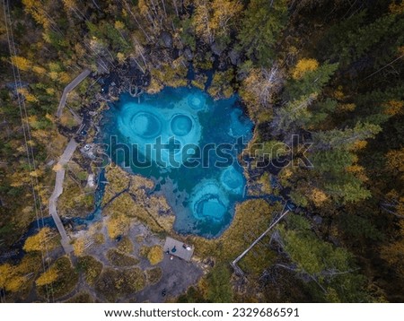The beautiful small lake with turquoise water in the middle of forest in Altai mountains, Siberia, Russia (aerial photo).