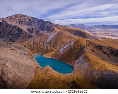 The beautiful small lake with turquoise water up high in the Altai mountains, Siberia, Russia (aerial photo).