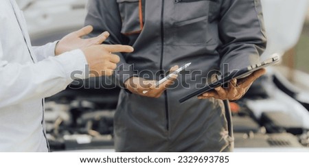 car service, repair, maintenance concept - Asian auto mechanic man or Smith writing to the clipboard at workshop warehouse, technician doing the checklist for repair machine a car in the garage,banner Royalty-Free Stock Photo #2329693785