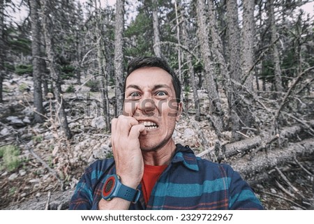 A frightened and lost male hiker looks around in the forest. The concept of meeting wild animals and phobia and accident in the woods Royalty-Free Stock Photo #2329722967