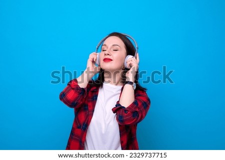 A young woman in a red shirt listens to music
