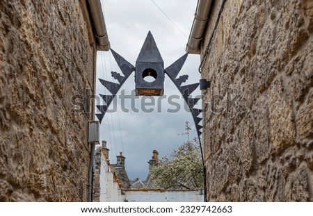 Looking down a alley at a metal spikey artfixture against the sky