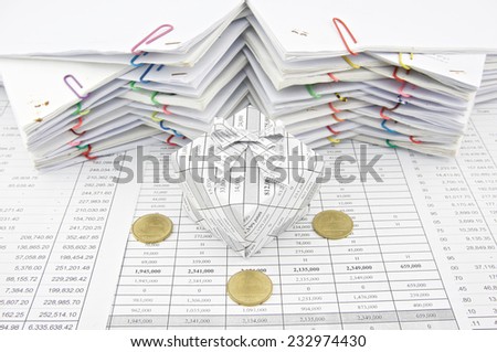 Gift box and gold coin place on finance account with pile of paperwork as background. Stack of paperwork is high as work hard. Business and finance concepts rich and successful photography.
