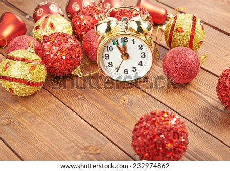 Festive New Year composition of a five to midnight time clock and multiple Christmas decorations over the wooden surface