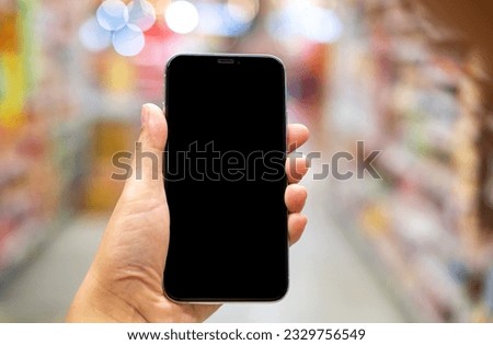 Hand holding black mockup smartphone and blurred background whit bokeh, telephone on the hand for presentation product and activities, life slyle concept Royalty-Free Stock Photo #2329756549