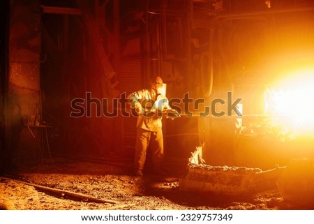 Metallurgists taking samples of liquid molten metal. Royalty-Free Stock Photo #2329757349