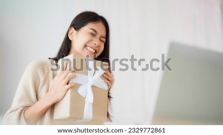 Young asian woman using computer laptop at home. Female showing gift box while on video conversation with friend. Happy birthday, Happy new year, Thanksgiving