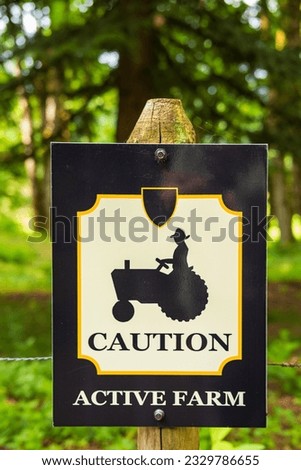 Wooden sign board with warning Caution Active Farm. Signs for farmhouse by the roadside in rural North America. Travel photo, nobody