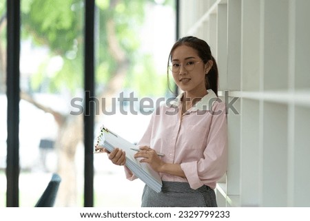 Young beautiful asian businesswoman holding unofficial spreadsheet paper accounting documents Division of documents to prepare the search Summarize the plan in a meeting at the office.