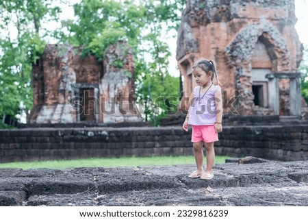 A young Southeast Asian girl walks to study the history of the ancient Khmer castle Khu Suan Taeng in Thailand, Buriram.