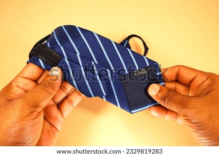 a necktie bottom side showing by hands with plain background close up view flat lay, hand holding necktie closeup 