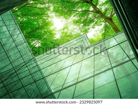 Eco-friendly building in the modern city. Sustainable glass office building with tree for reducing heat and carbon dioxide. Office building with green environment. Corporate building reduce CO2. Royalty-Free Stock Photo #2329825097
