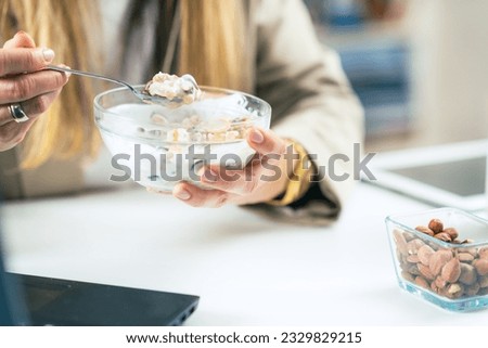 The power of healthy eating at work as a woman indulges in a delicious combination of muesli and yogurt. This nutritious meal provides a satisfying boost to her day Royalty-Free Stock Photo #2329829215