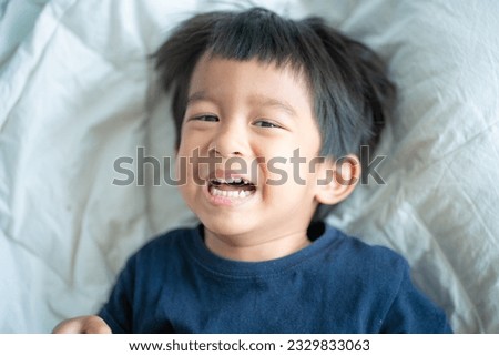 4 year asian boy laughing while lying on white bed happy boy