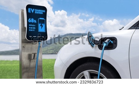 Electric car plugged in with charging station to recharge battery by EV charger cable with nature and lake background. Future innovative ev car and energy sustainability. Peruse