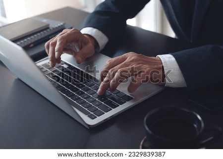 Businessman online working on laptop computer, surfing the internet, networking at modern office, closeup. Business man hand typing ob laptop computer keyboard on office desk