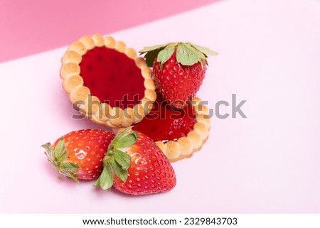 Strawberries and biscuits with strawberry jam on a pink background.