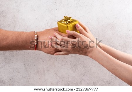 Happy Raksha Bandhan Holiday Background. Indian brother wearing rakhi bracelet is giving gift box to his sister. Royalty-Free Stock Photo #2329869997