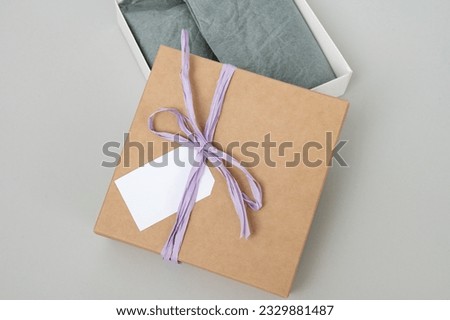 Boxes for parcels made of kraft paper on a gray background. Gift box with a tag for text, logo. A place for text, a ribbon with a bow on a gift box, a greeting card