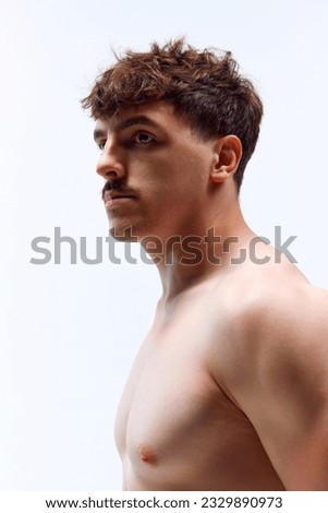 Portrait of young handsome man posing shirtless with serious facial expression against grey studio background. Muscular body. Concept of man's beauty, sportive and healthy lifestyle, athletic body Royalty-Free Stock Photo #2329890973