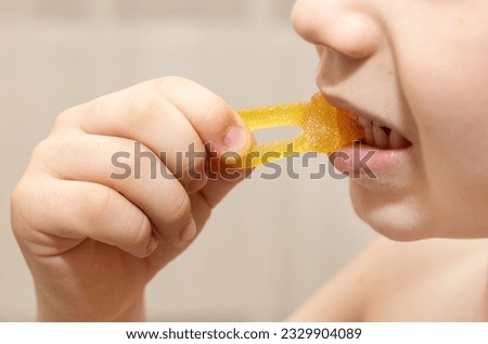 many jelly gummy candy, worm or butterfly shape on table kid hands.child boy is lying with candies on face and in mouth.smiling kid eating unhealthy dessert with sugar.crazy photos
