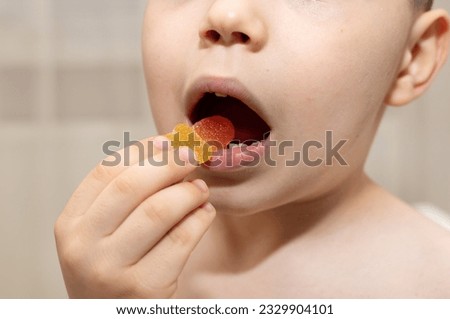 many jelly gummy candy, worm or butterfly shape on table kid hands.child boy is lying with candies on face and in mouth.smiling kid eating unhealthy dessert with sugar.crazy photos