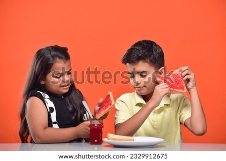 Children having breakfast with milk,bread, jam. Sister and brother sitting at the table at home having breakfast