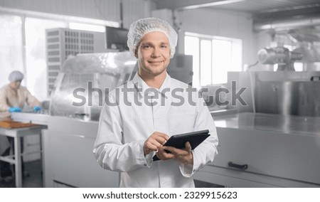 Chocolate factory worker inspecting production line conveyor with sweets candy. Concept food industry banner.