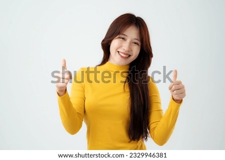 Portrait of young asian girl laughing with showing thumps up at camera. Isolated on white background. Royalty-Free Stock Photo #2329946381