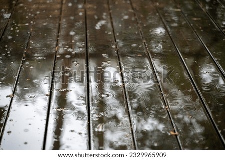 Rain drops on wet wooden floor of patio at raining day Royalty-Free Stock Photo #2329965909