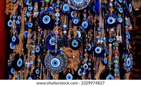A lot of key rings and pendants, bracelets with a blue eye, amulets, beads from the evil eye in the souvenir shop of the Turkish city Royalty-Free Stock Photo #2329974827