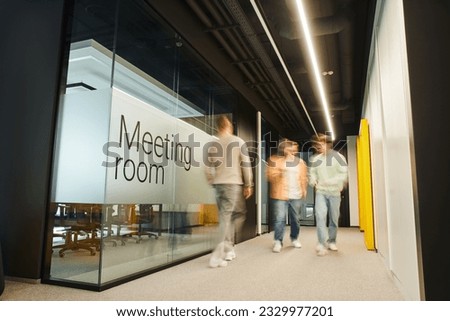 motion blur of energetic and ambitious business people walking near meeting room in coworking environment of modern office with high tech interior, full length, dynamic business concept Royalty-Free Stock Photo #2329977201