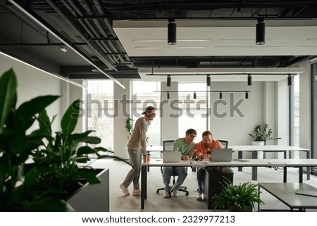 creative and successful team in stylish casual clothes working near laptops at workplace in contemporary coworking environment with high tech interior, business collaboration concept, banner Royalty-Free Stock Photo #2329977213