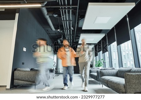 motion blur of modern entrepreneurs in casual clothes walking along lounge corridor with comfortable couches in coworking office with high tech interior, movement, collaboration, dynamic business Royalty-Free Stock Photo #2329977277