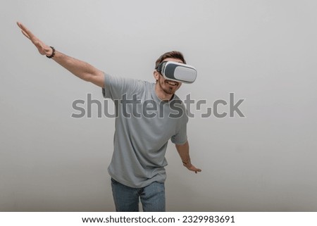 Futuristic man wearing virtual reality glasses interacts with the air in an isolated gray background.