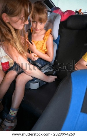the mother fastens the child with a safety belt