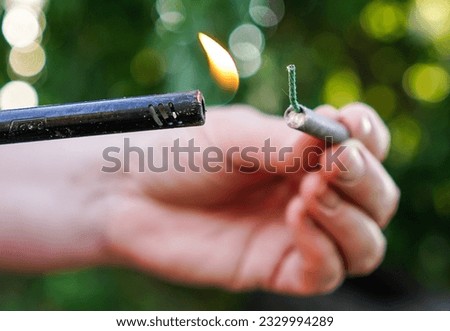 Person fire up firecracker. Person holding lighter and firecracker. Shooting firecrackers and fireworks. Royalty-Free Stock Photo #2329994289