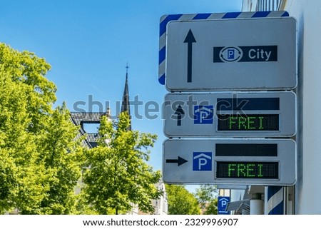Information board on the wall of a city building indicating free parking spaces. Clear blue sky above the city.