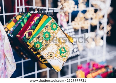 Closeup of multi-colored patterned purses on a rack of product display. Selective focus. 