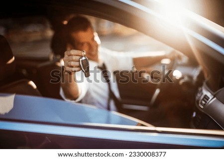 Businessman looking at the camera and holding a car key fob