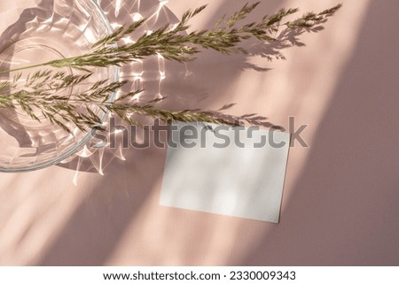 Aesthetic lifestyle feminine flatlay, blank paper card mockup, meadow glass on a pink beige background with abstract sunlight shadows