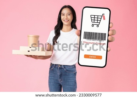 Studio shot of Beautiful Asian woman holding pizza boxes and smartphone with scan barcode for discount code coupon on pink background. Royalty-Free Stock Photo #2330009577