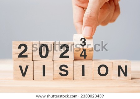 hand flipping block 2023 to 2024 VISION text on table. Resolution, strategy, goal, motivation, reboot, business and New Year holiday concepts
