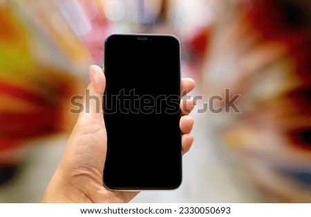 Hand holding black mockup smartphone and blurred background whit bokeh, telephone on the hand for presentation product and activities, life slyle concept Royalty-Free Stock Photo #2330050693