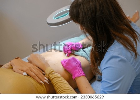 Young beautiful female dermatologist doing hair removal treatment on patient's bikini zone with electrolysis. Epilation and beauty concept. High quality photo