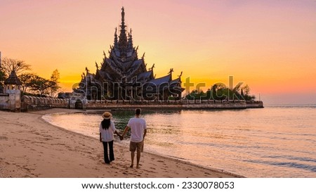 A couple of men and women visit the Sanctuary of Truth, Pattaya, Thailand, wooden temple by the ocean during sunset on the beach of Pattaya. Royalty-Free Stock Photo #2330078053