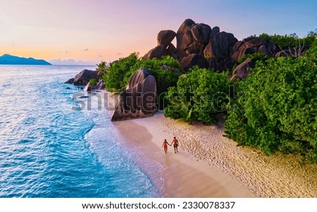 Anse Source d'Argent beach, La Digue Island, Seyshelles, Drone aerial view of La Digue Seychelles bird eye view.of tropical Island, couple men and woman walking at the beach during sunset at a luxury Royalty-Free Stock Photo #2330078337