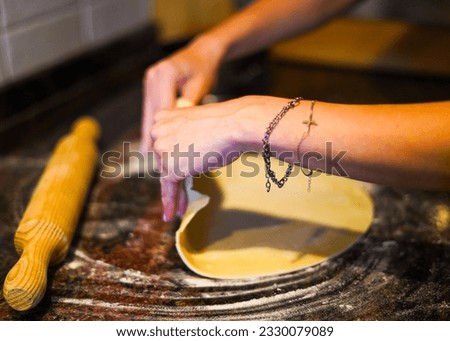 kneading a dough with a rolling pin with both hands on a black marble kitchen