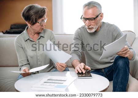 Senior couple calculating utility bills, paying the loan or checking domestic finances. People managing monthly budget and doing tax paperwork at home Royalty-Free Stock Photo #2330079773